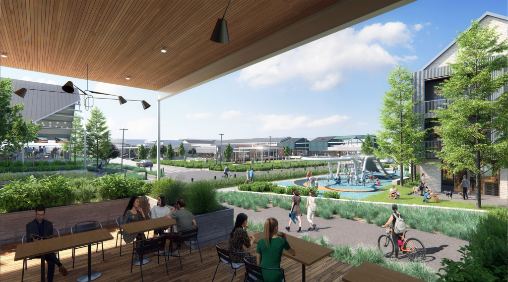 Perspective rendering from a covered patio at Assembly Park, showing outdoor dining tables overlooking a landscaped plaza with walking paths, planted seating areas, and a children's play zone. In the background, retail storefronts and a stage structure provide an active gathering space.