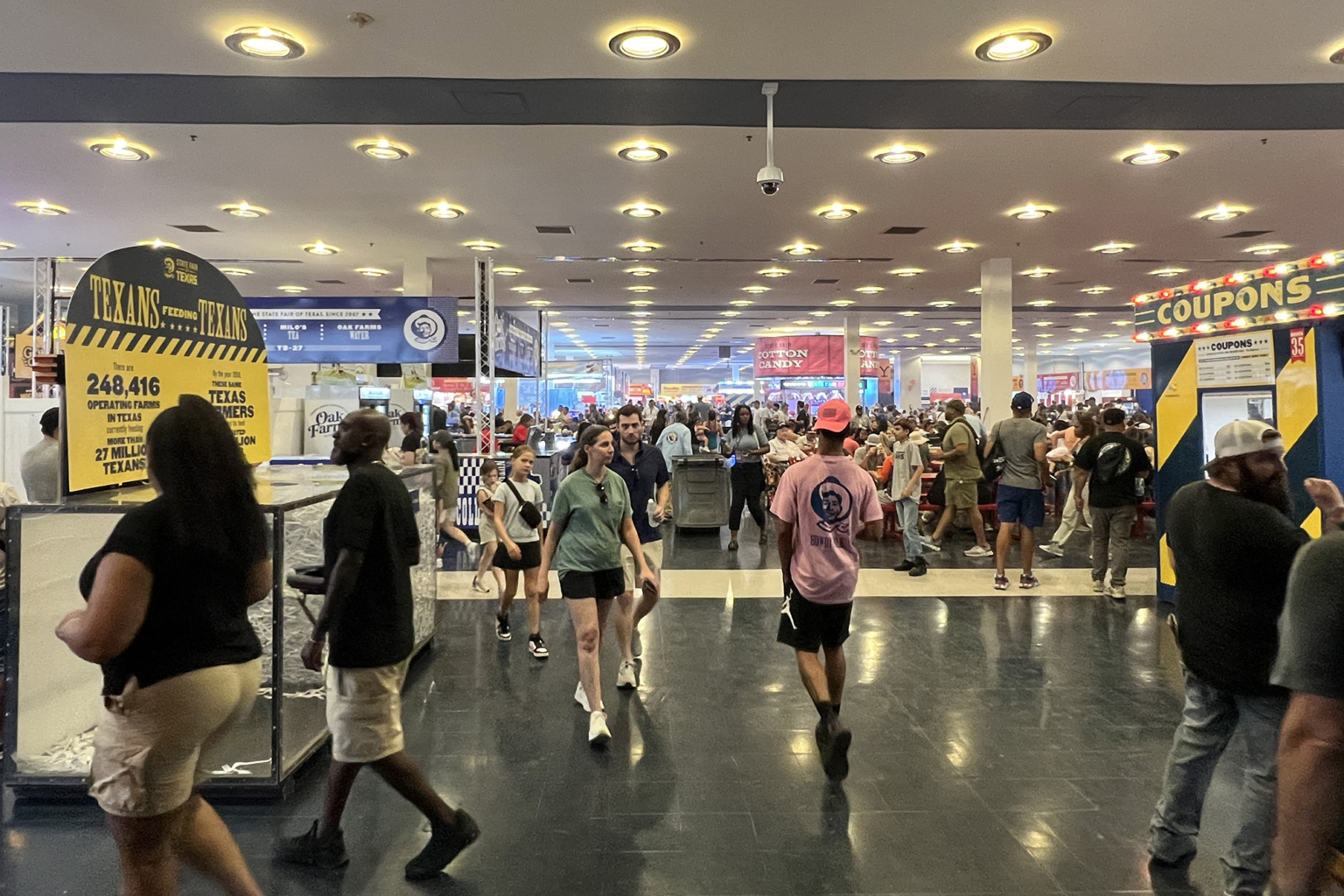 Interior of the Fair Park Tower Building, featuring the exhibit and food hall with visitors walking and seated at tables.