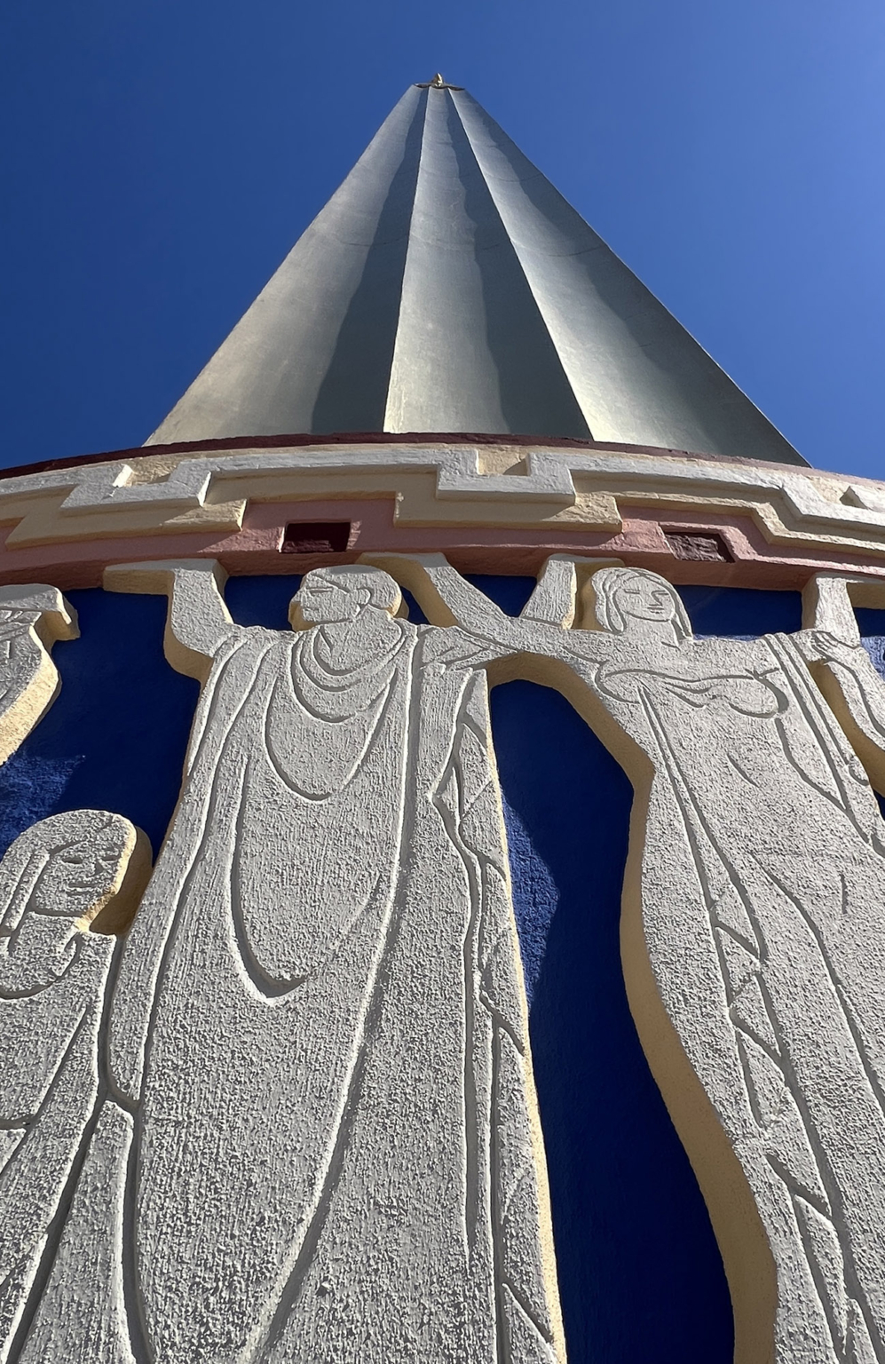 Upward view of the restored tower on the Fair Park Tower Building with gold details against a clear blue sky.