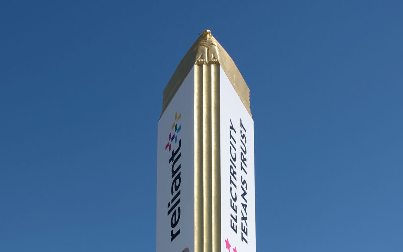 Fair Park Tower Building with its gold-clad spire and surrounding seating plaza on a sunny day.