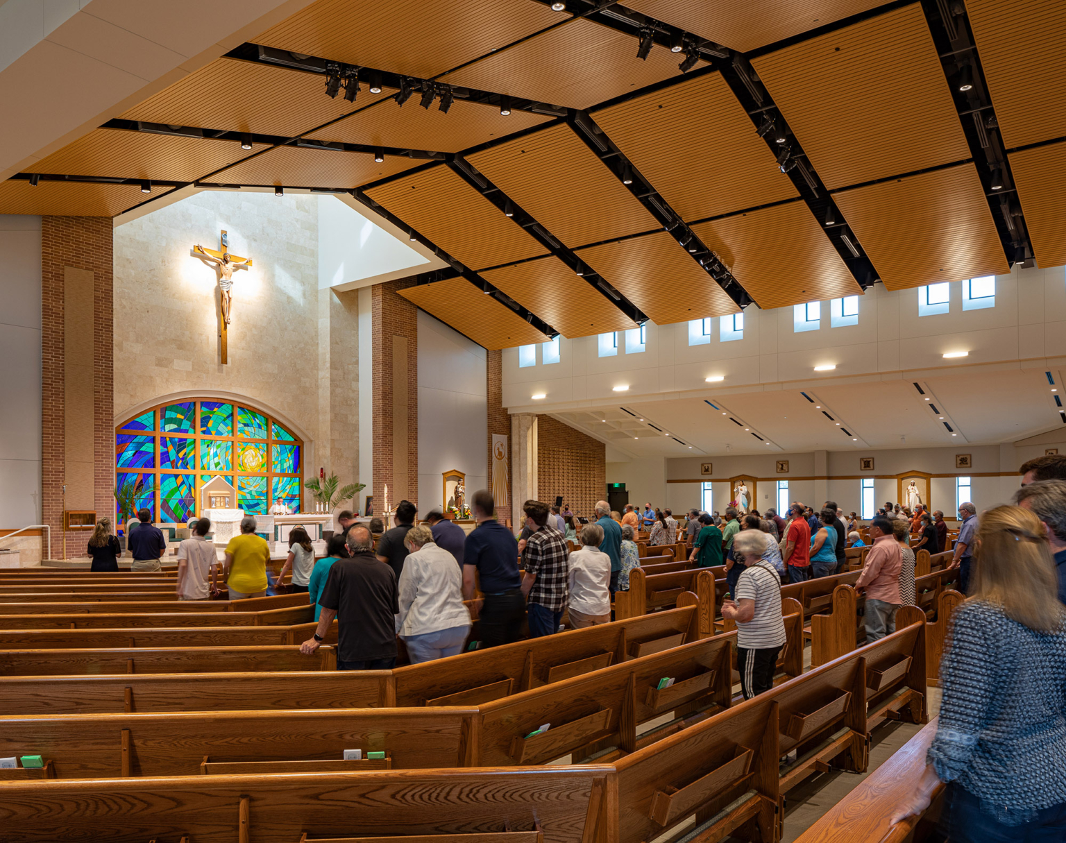 Interior view of the nave showing fan-shaped seating for 1,000 people, stained wood ceiling panels, clerestory windows, and natural light.