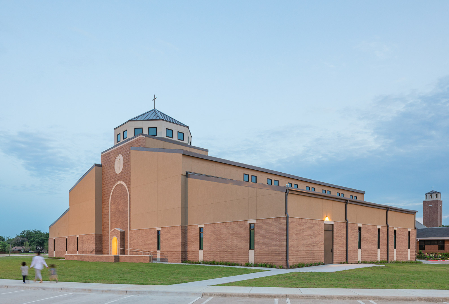 Side view of the church exterior with complementary brick tones, projecting courses, and standing seam metal roofs.
