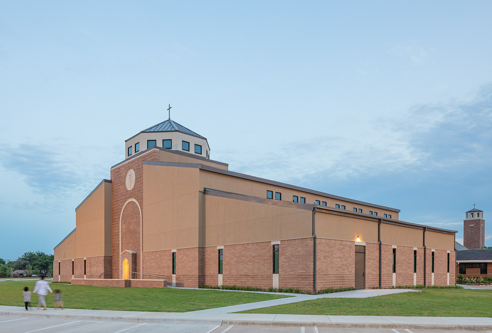 Exterior Side view of the church exterior with complementary brick tones, projecting courses, and standing seam metal roofs.