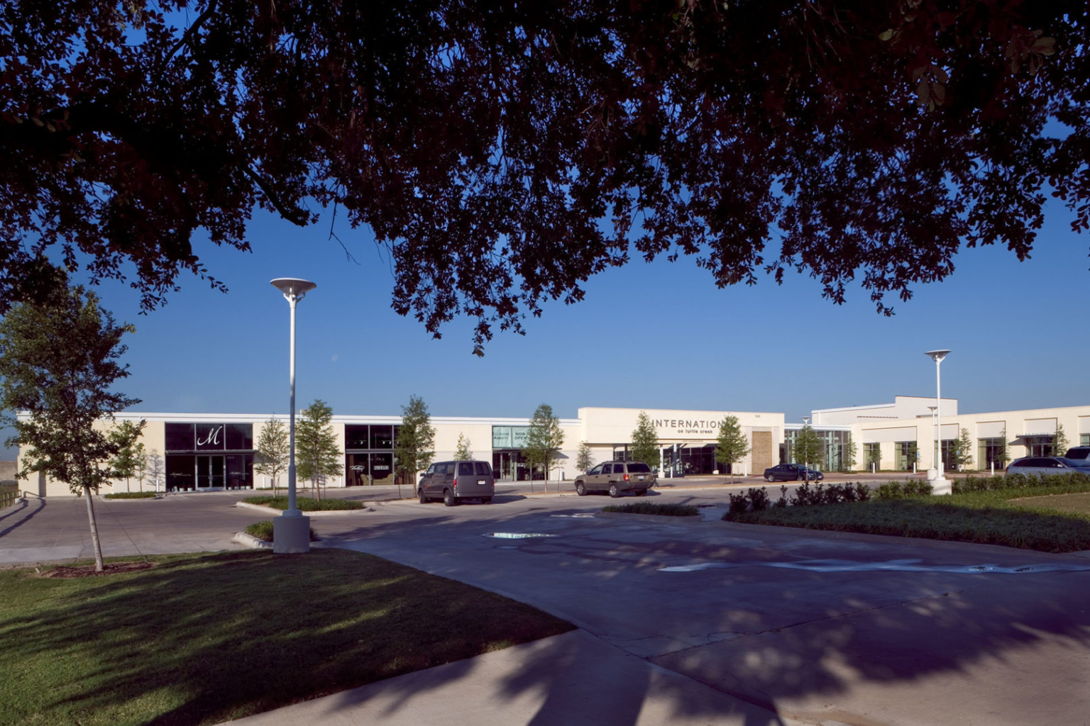 A wide-angle view of the repurposed International on Turtle Creek building with landscaped parking and showroom entrances.