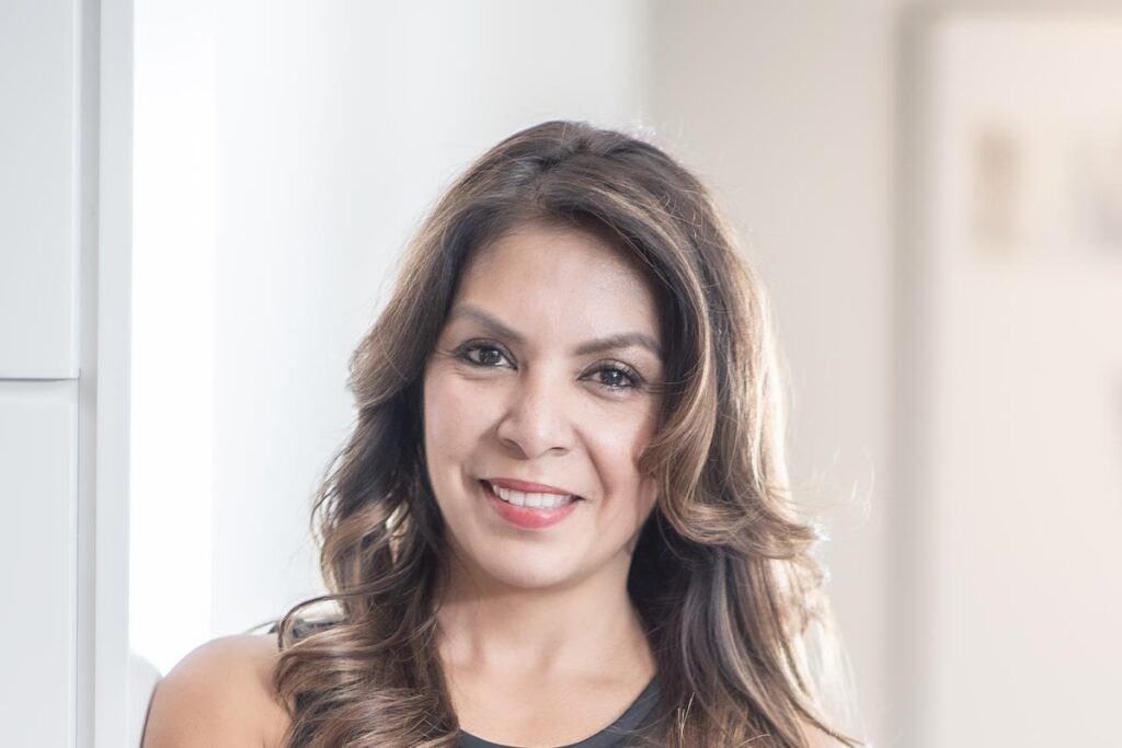Christina Astion, Executive Assistant at GFF, close-up professional portrait in a modern Dallas design firm setting.