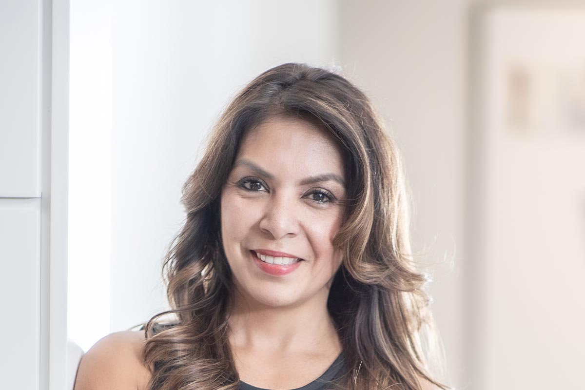 Christina Garcia, Executive Assistant at GFF, close-up professional portrait in a modern Dallas design firm setting.