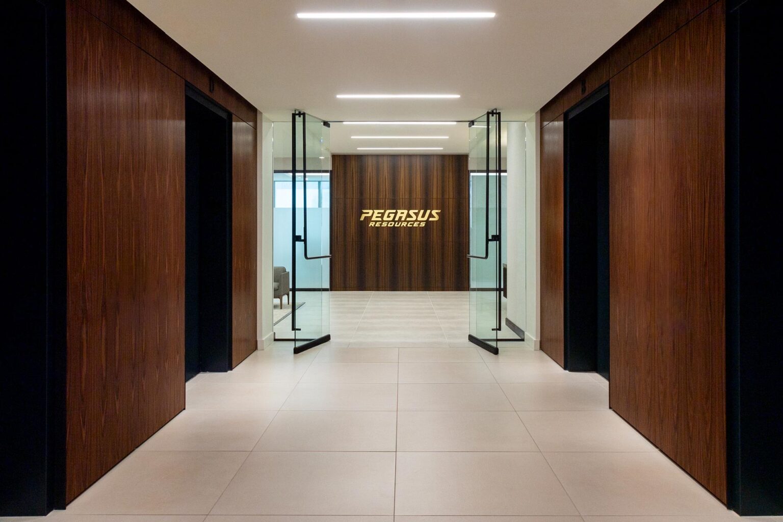 Corporate office lobby with glass double doors and dark wood-paneled walls.