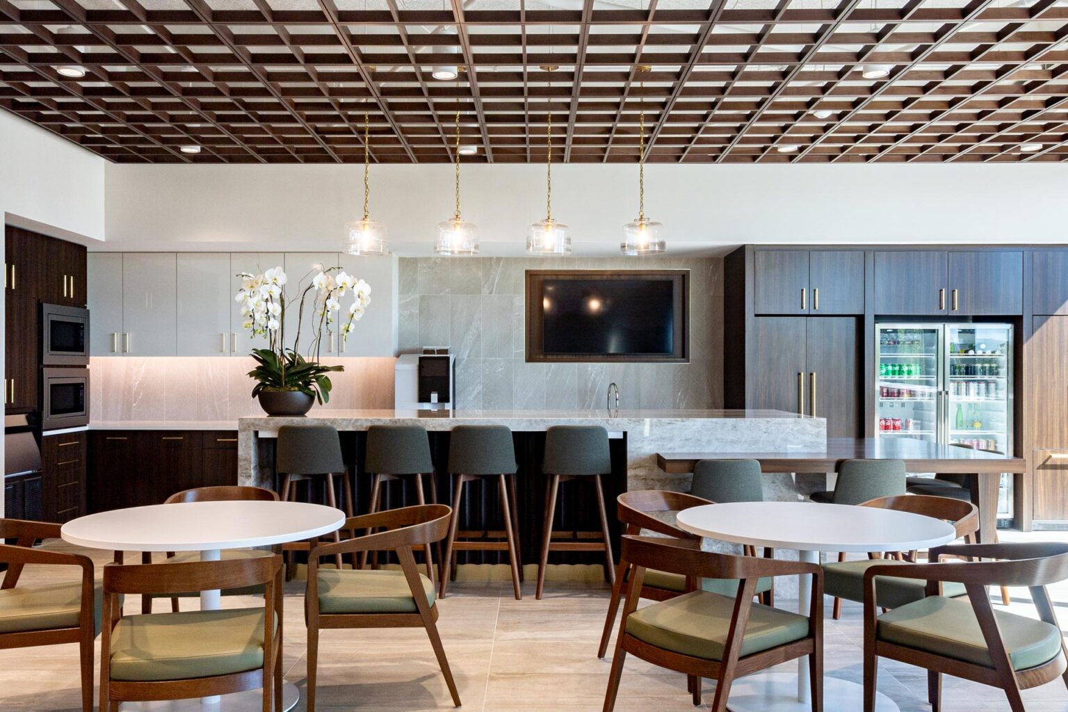 Break room with tall bar seating, built-in appliances, wood cabinetry, and orchid centerpiece.