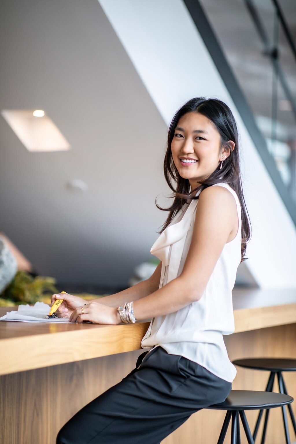 Amanda Choi, Architectural Professional at GFF, photographed in a Dallas design firm office, working at a modern wood counter.