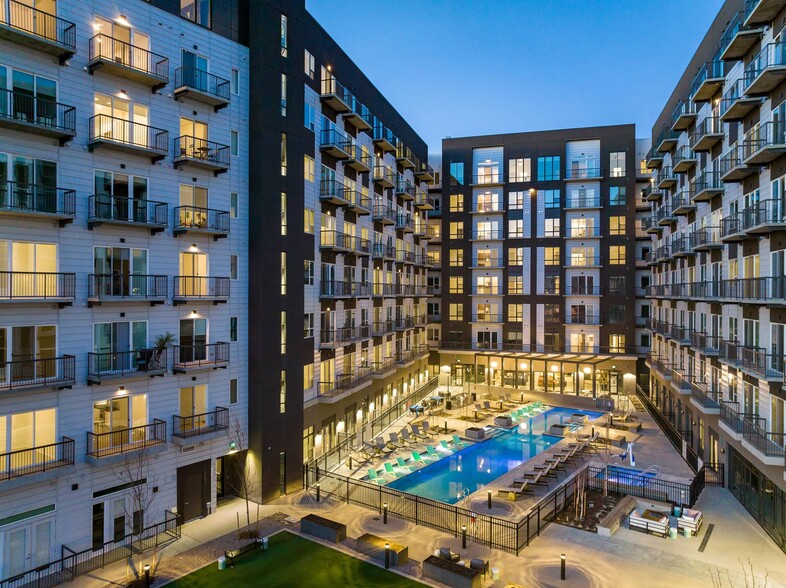 Denargo Market Phase 3 courtyard view at dusk with illuminated swimming pool, lounge seating, turf lawn, and surrounding mid-rise residential balconies in Denver’s RiNo neighborhood.