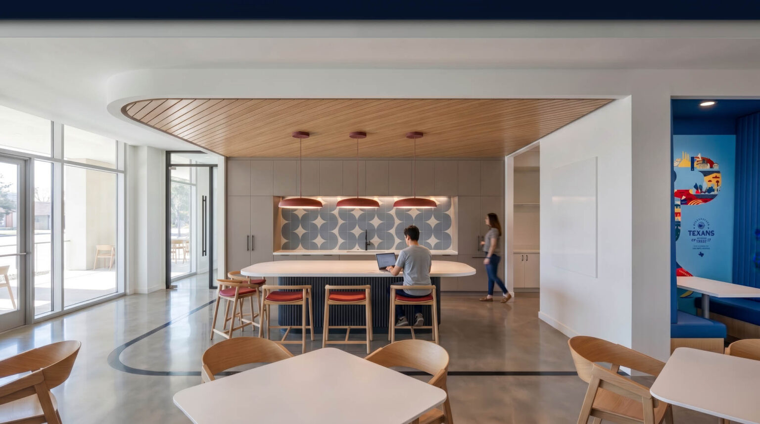 Staff breakroom at the State Fair of Texas Administration Building with daylight, patterned tile, wood ceiling, island seating, and colorful State Fair graphics.