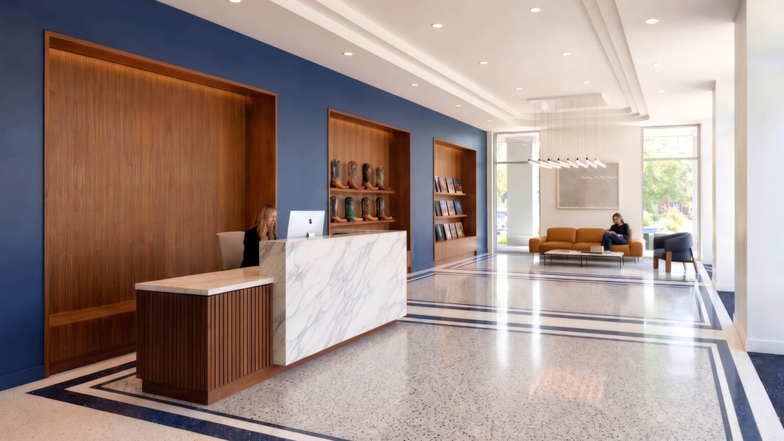Lobby reception area at the State Fair of Texas Administration Building with terrazzo flooring, blue walls, wood display niches, reception desk, and seating.