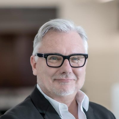 A cropped landscape portrait of Chris Andersen, Associate Principal and Senior Project Leader at GFF, smiling in a softly lit interior setting.