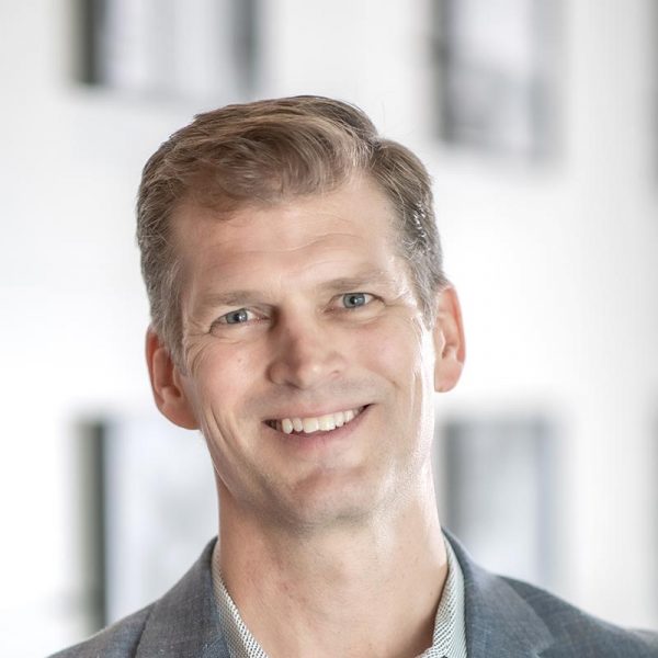 Grant Wickard, AIA, Associate Principal and Senior Project Leader at GFF, close-up portrait with blurred office background.