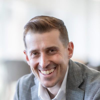 Jason Cave, Associate Principal and Director of Civic Practice at GFF, close-up portrait in soft daylight wearing gray blazer.