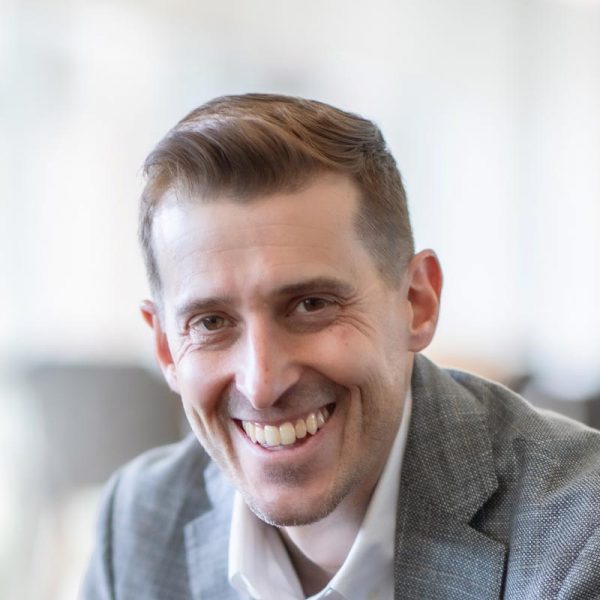 Jason Cave, Associate Principal and Director of Civic Practice at GFF, close-up portrait in soft daylight wearing gray blazer.