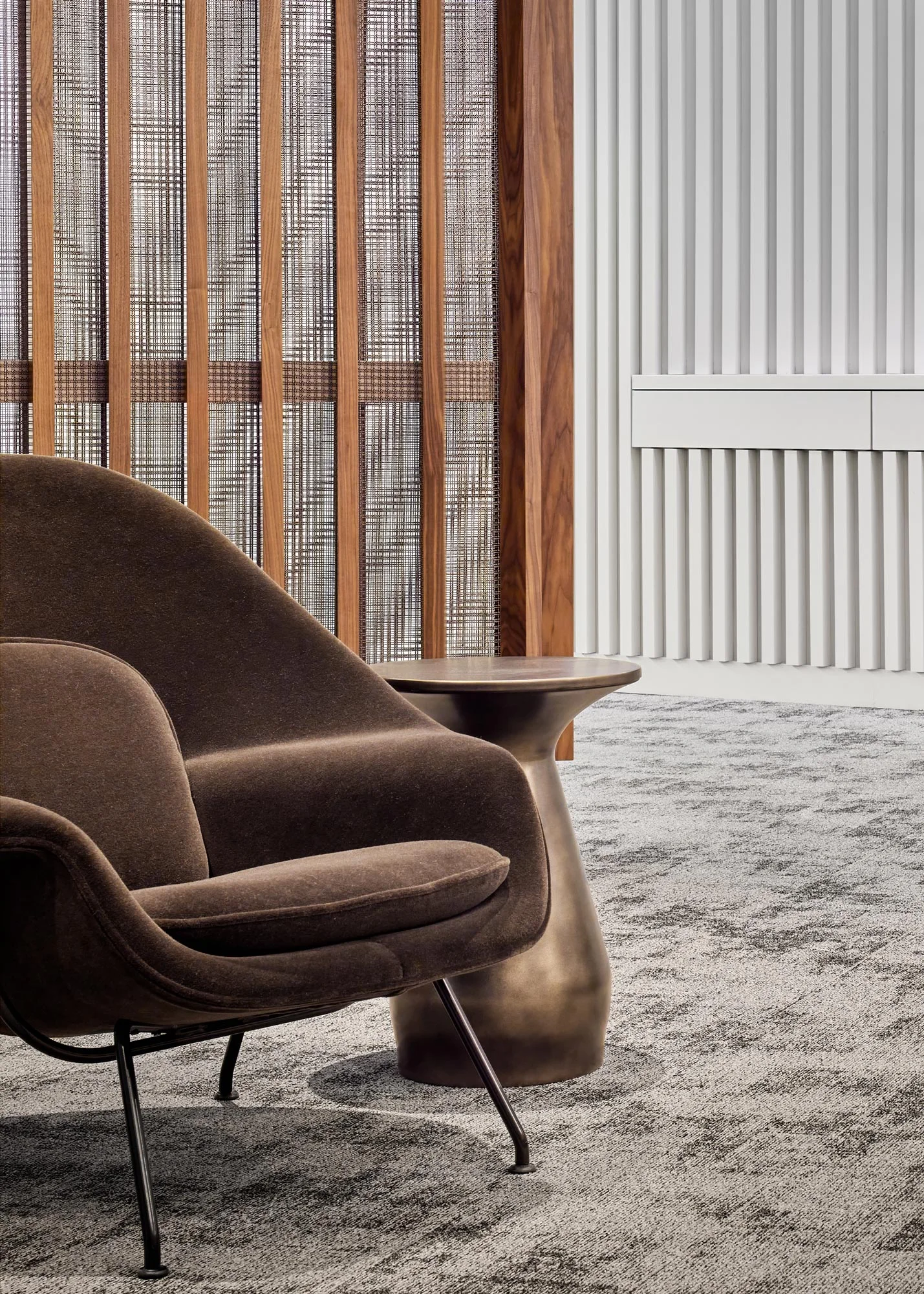 Detail of GFF’s office lounge with walnut slat walls, fluted white millwork, and sculptural modern furniture, highlighting material warmth and workplace design sophistication.